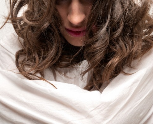 Young insane woman with straitjacket looking at camera close-up portrait